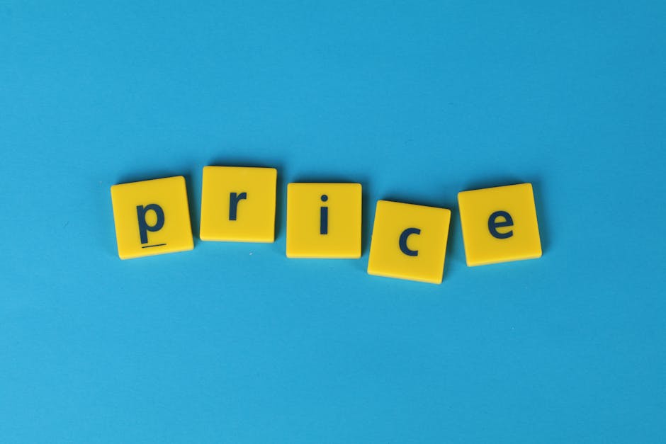 A photograph displays the word 'CHEAPAS' spelled out with small, square, bright pink tiles featuring black letters and point values typical of Scrabble game tiles, arranged on a plain white background
